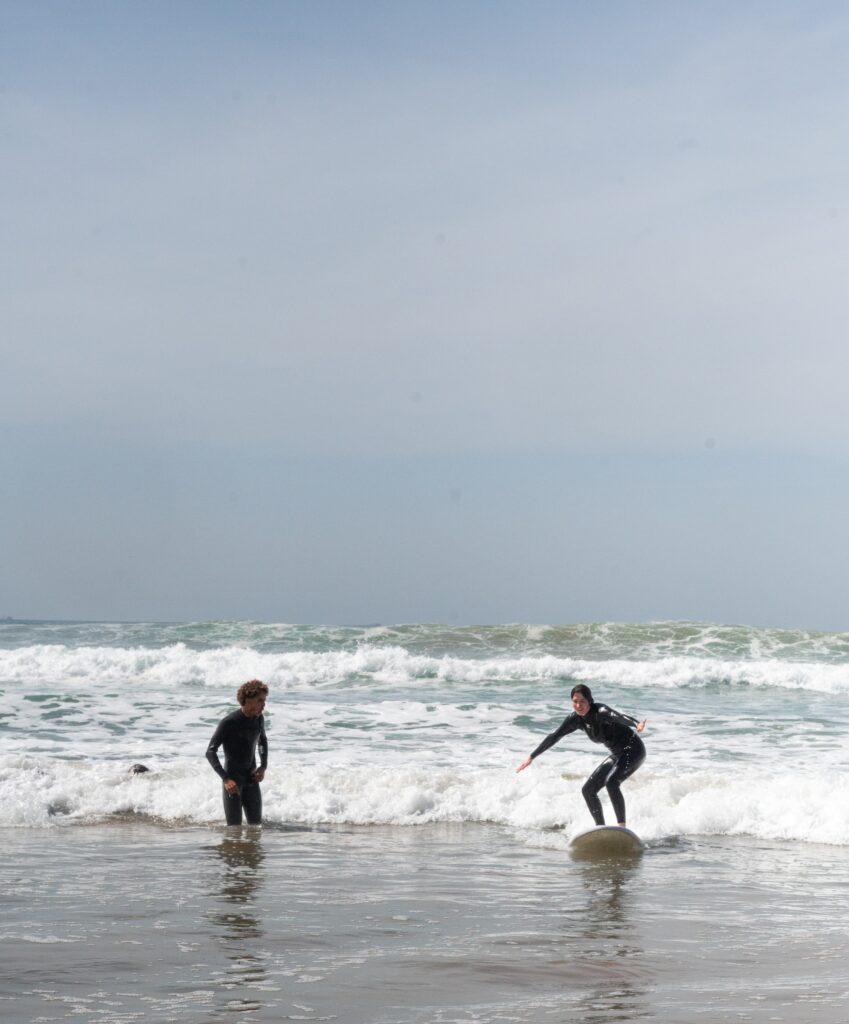 Coach Samado guiding a beginner surfer during a lesson in Morocco.